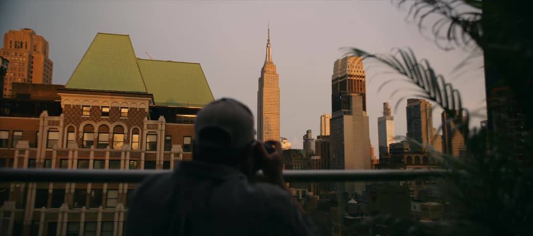 Man in a cap photographing the skyline of a metropolis with a skyscraper