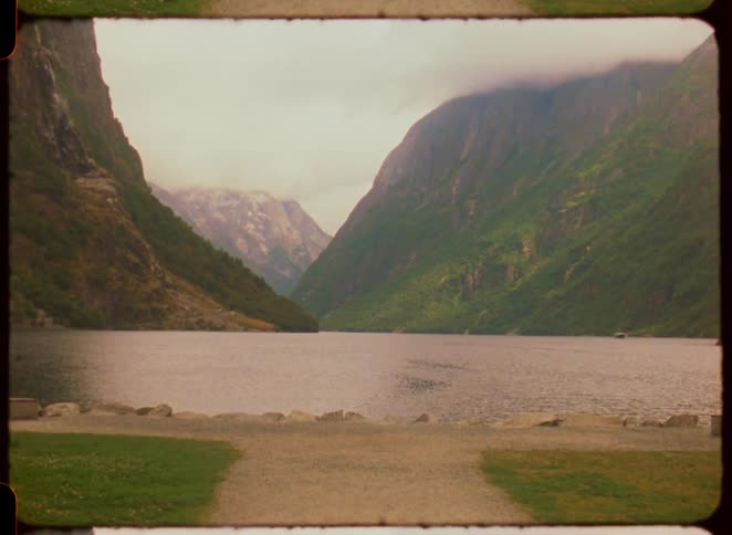 A serene fjord with green mountains under a cloudy sky