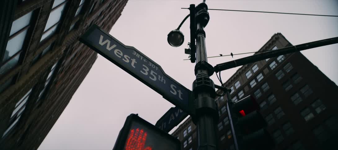 A street sign at a city intersection surrounded by tall buildings