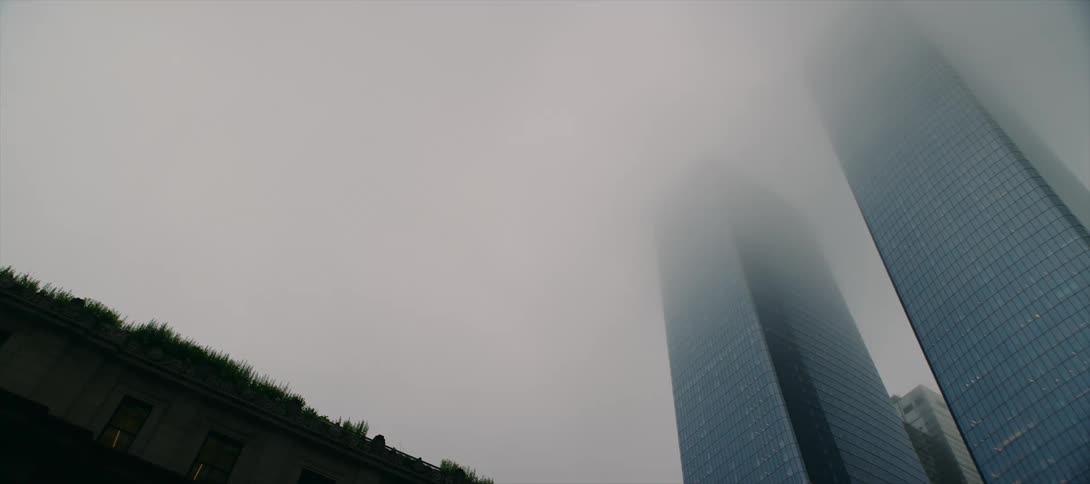 The tops of two tall skyscrapers are engulfed in thick fog
