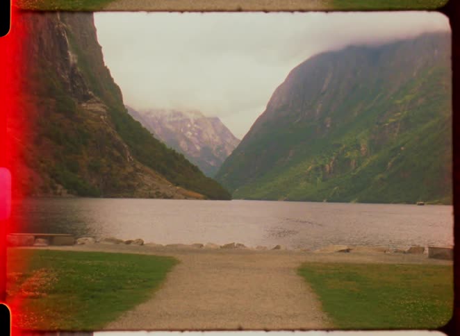 A landscape of a large lake in the middle of mountains covered with green vegetation