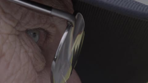 An elderly man looks through glasses