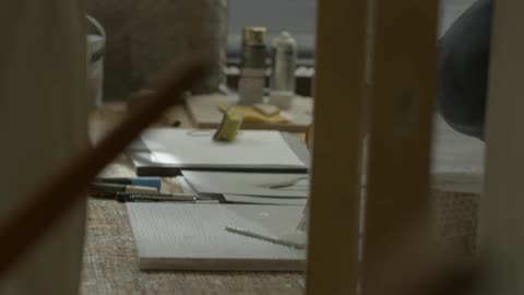 A person crouches and applies paint to a tile