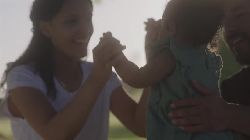 Parents smile while holding baby outdoors