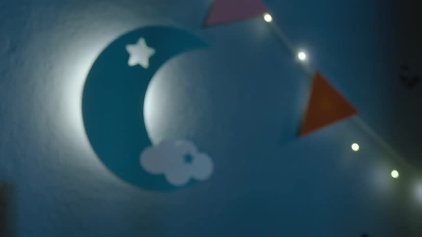 Light glows from a crescent moon decoration and a nearby string of lights at night