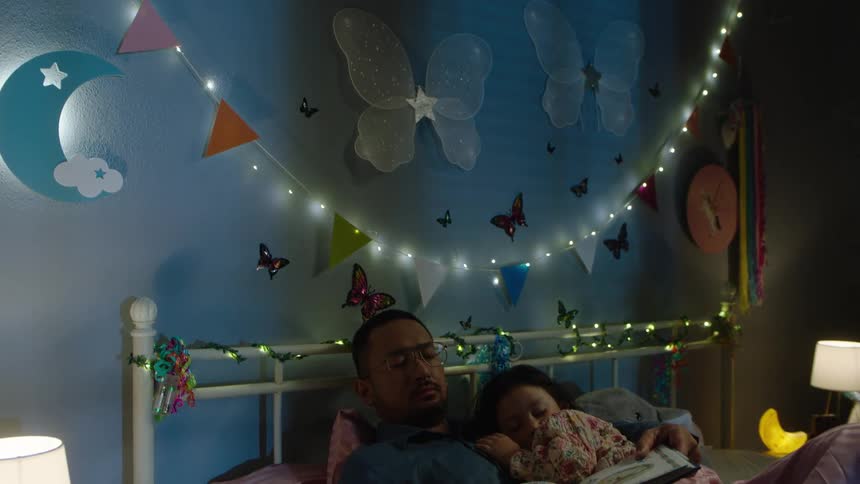 Father sleeps next to his daughter having fallen asleep while reading her a bedtime story