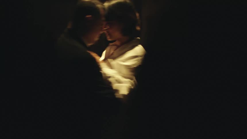 A couple shares a slow dance in a dimly lit room