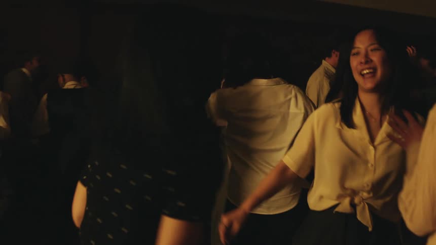 People smile while dancing on a crowded dance floor