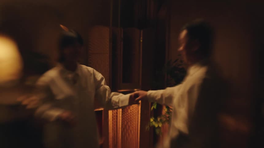 Couple smiles while dancing hand in hand in a cozy setting