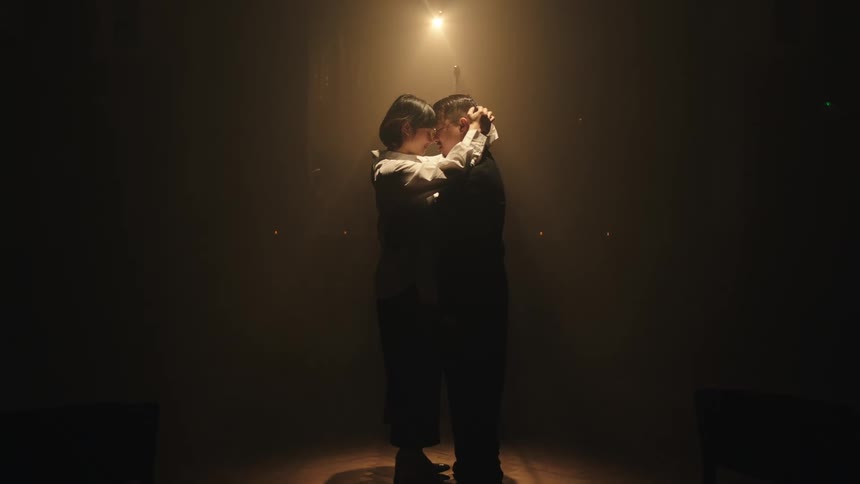 A couple are dancing under a spotlight
