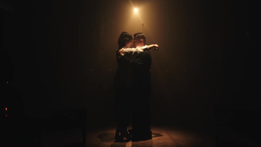 A man and woman dance in the club under a spotlight