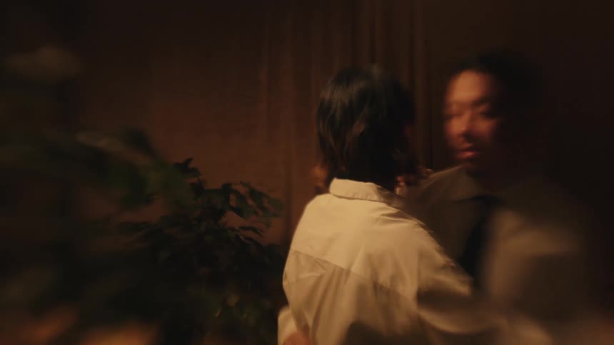 A man and woman are joyfully dancing together in a dimly lit room with the man twirling the woman as they both smile and laugh