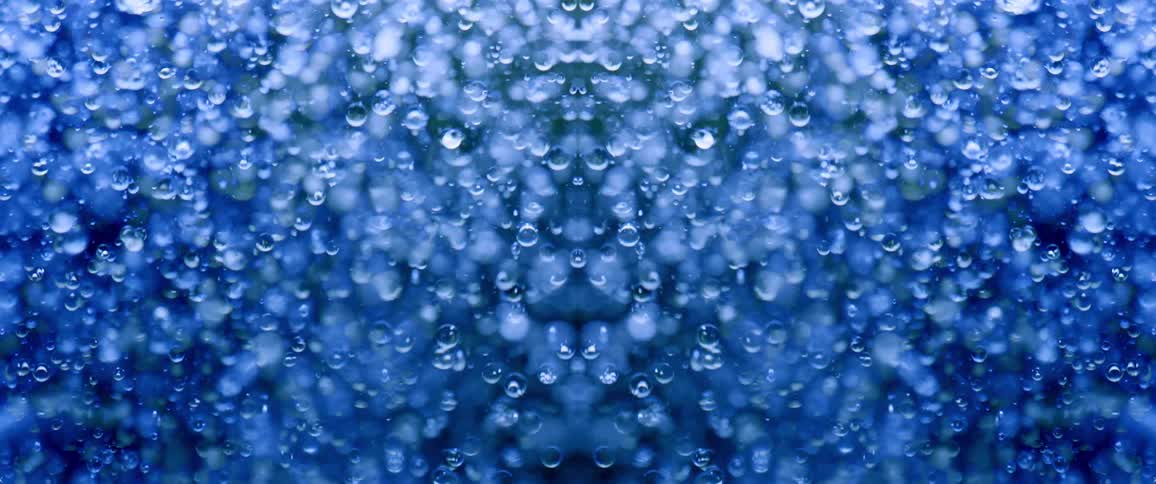 A field of blue bubbles or droplets with a reflective surface flows upward and downward in a symmetrical pattern