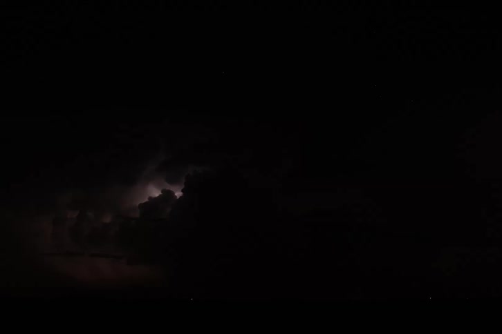 A series of lightning strikes illuminating the clouds in the night sky