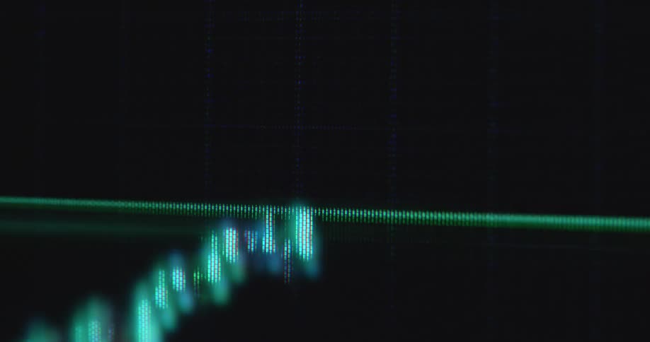 Bright neon green bars or candles of a candlestick chart pattern or financial graph on computer display screen with dark background and positive price development symbolizing successful stock trading with upward trend and handheld camera movement