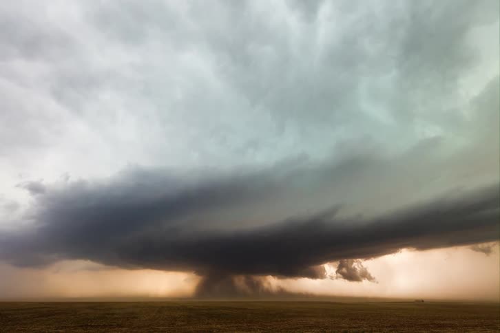 A massive storm cloud looms over an open plain