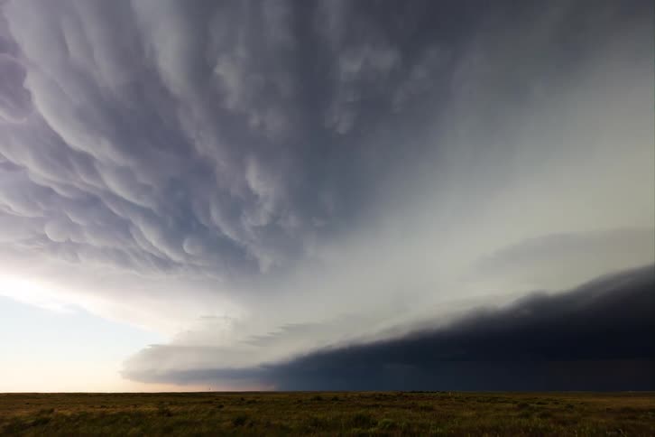 Stormy clouds over a grassy plain area outdoors during dusk or dawn
