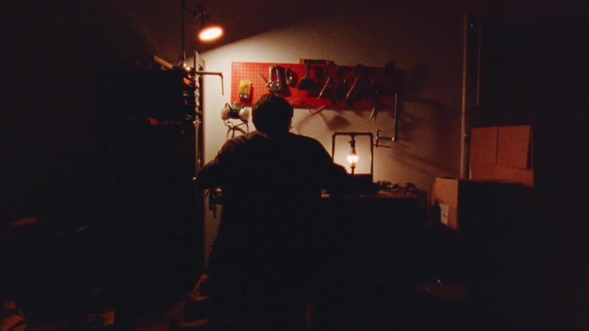 The man is in the workshop grabbing tools