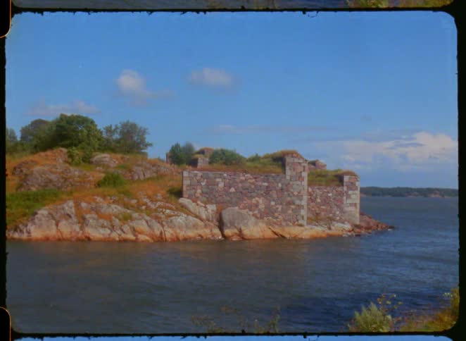Stone fortification by the sea on rocks surrounded by vegetation