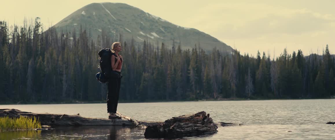 Female hiker stops on the shore of a lake and looks around