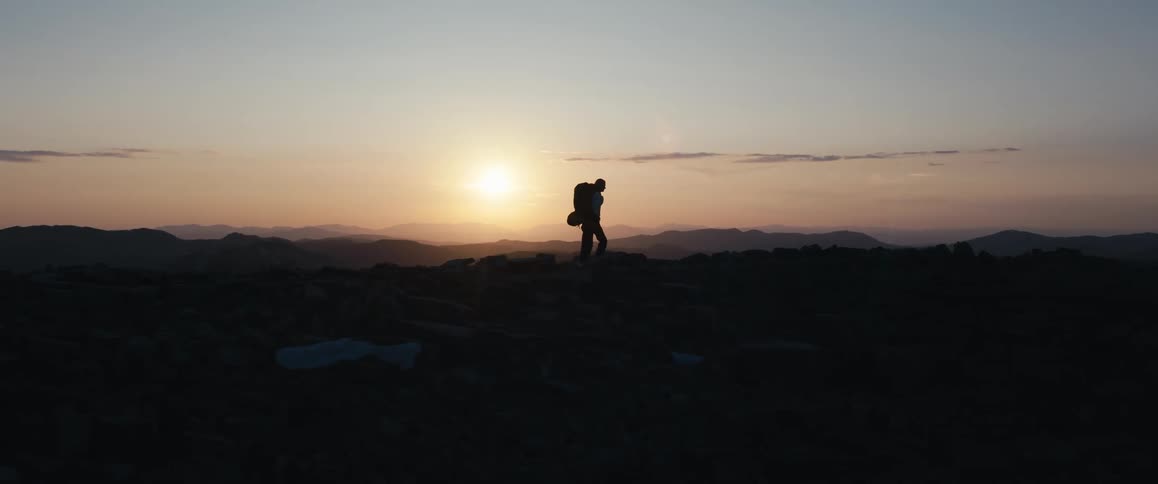 The man is hiking on the mountain at sunrise