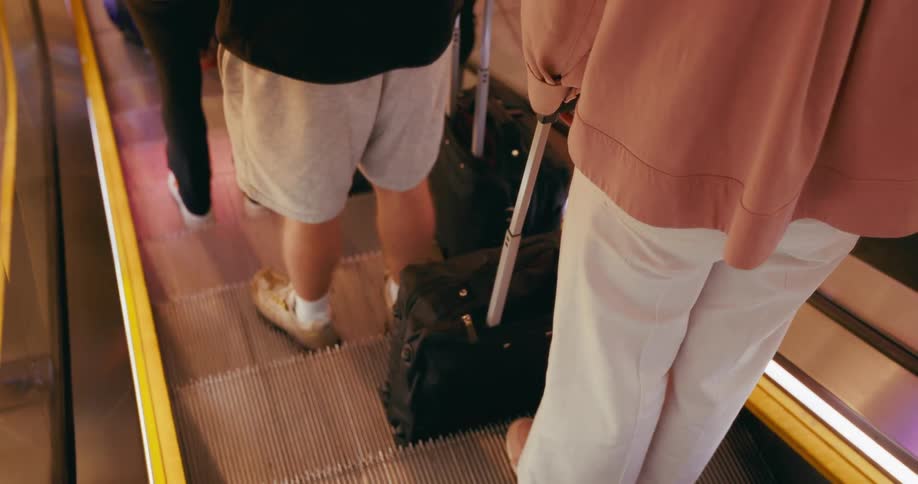 People with luggage on an escalator at an airport or transit hub