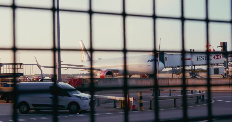 Vehicles moving near a parked plane at an airport