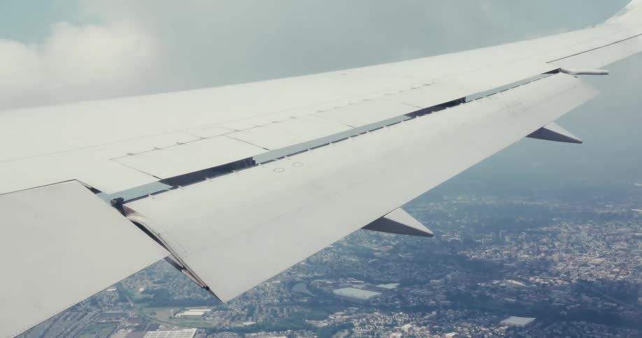 Airplane wing seen during flight over the city