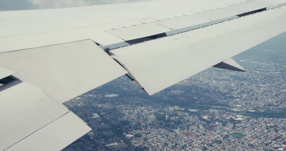 The plane flies high over the town