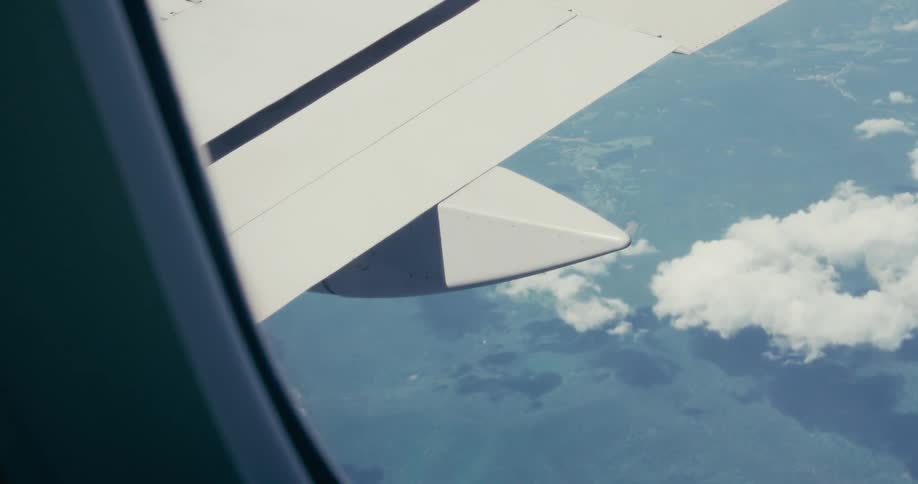 Interior view from plane window looking out to clouds below
