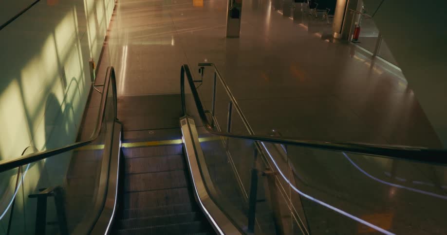 An empty airport terminal hallway seen from an escalator