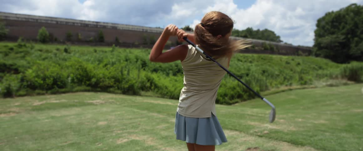 Young girl practicing her golf swing on the golf course