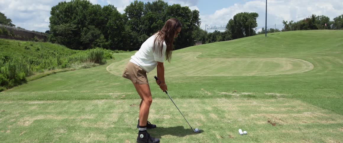 Young woman playing golf with a male child and another woman outdoors during day time