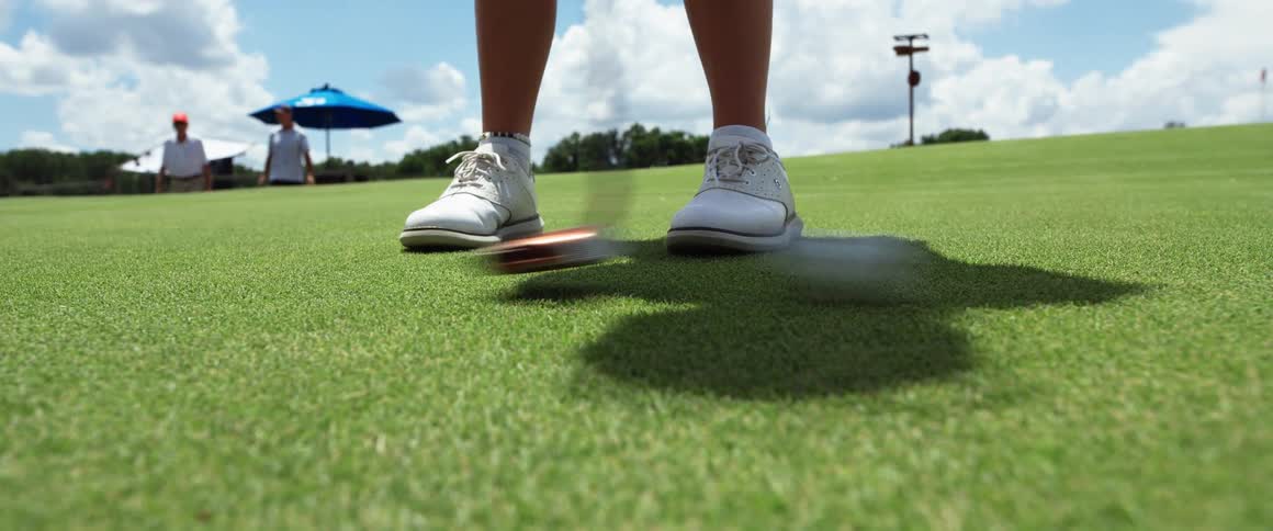 A person hitting a golf ball with a golf club on a golf course at midday