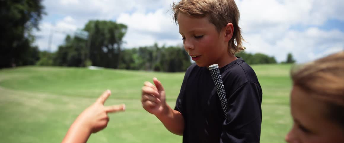 Children are playing rock paper scissor on the golf course