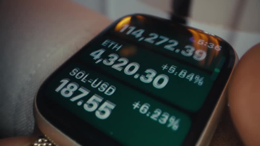 The video shows a closeup shot of a smartwatch displaying a ticker of stock and cryptocurrency prices the display shows the company or currency ticker its current price and the percentage change