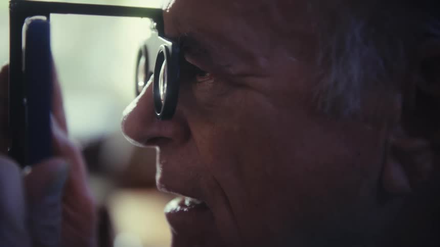 A person with a hand holds a device with a lens to their face and looks through it