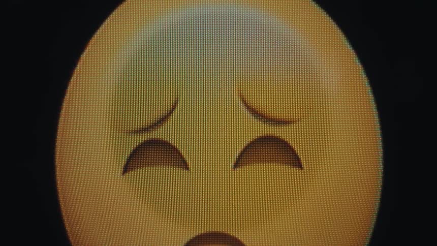 The video shows an animation of a sad emoji initially its face is upside down with a downturned mouth and wide sad eyes it then slowly flips rightside up and its eyes close as it appears to fall asleep