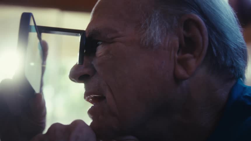 A person with a device with a lens to their face looks through it with an open mouth and an expression