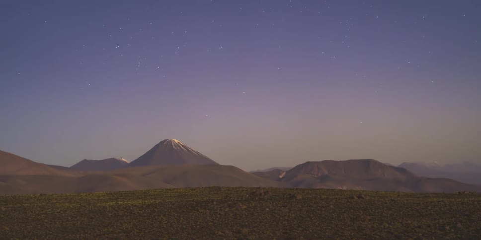 Volcano and mountains are shown in a timelapse from day to night