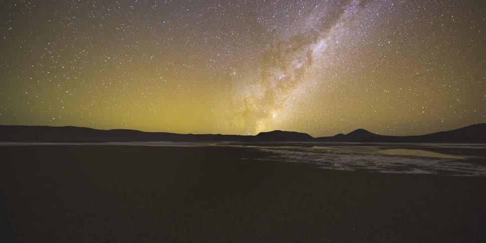 Starry sky with the milky way visible above mountains and a lake in the background