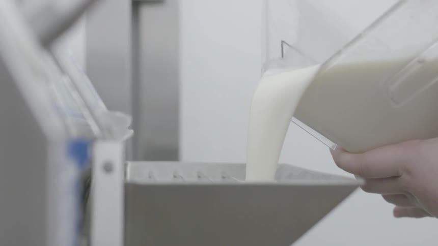 A woman pours a liquid mixture into a machine