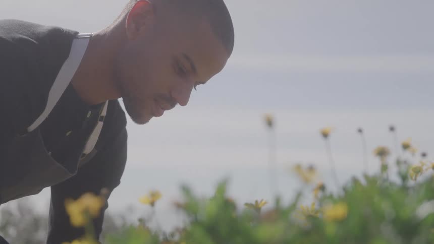 Man in apron outdoors facing yellow flowers