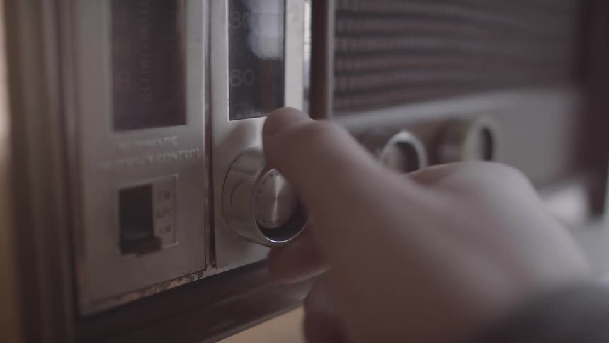 The person turns the dial on the radio