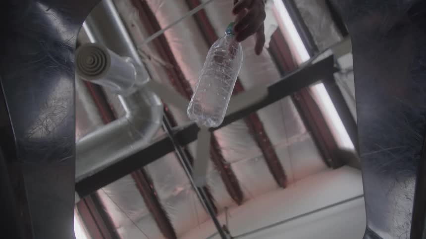 A plastic bottle is dropped in the garbage