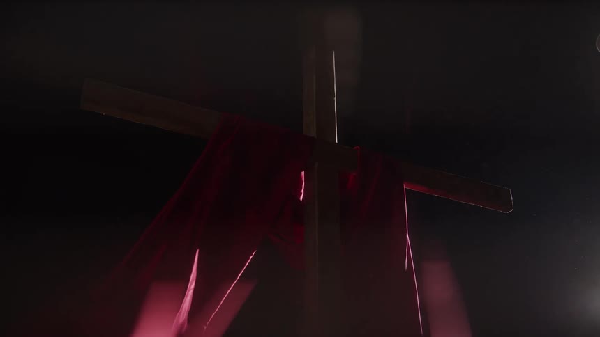 A cross with red cloth on it with a light on the object