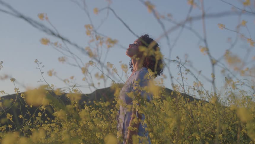 The woman is looking up at the sky on the field