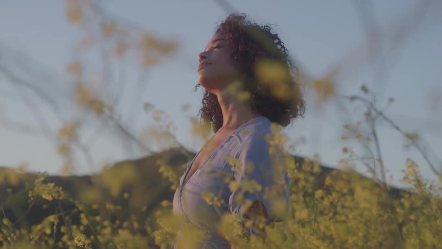 The woman is looking up at the sky with her eyes closed