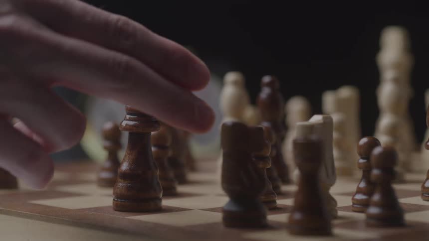 Hand moves a piece during a chess game
