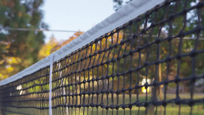 Tennis ball hitting the net on an outdoor court
